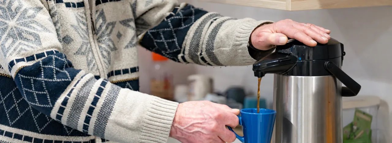 Iemand neemt een bakkie koffie uit de thermoskan in activeringscentrum Kreileroord