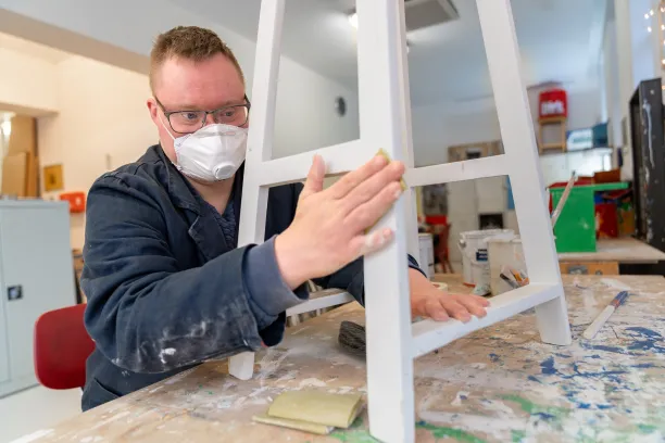 Een man in een werkplaats werkt aan een houten meubel