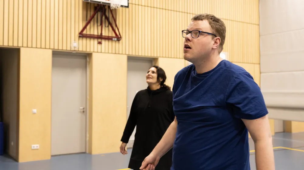 Een man en een vrouw in een sportzaal kijken naar de bal