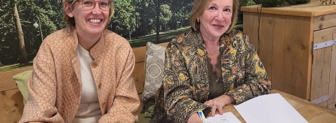 Twee bestuurders ondertekenen de overeenkomst, beide dames lachen