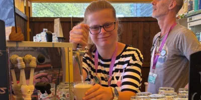 Carola kijkt camera in terwijl ze een drankje aan het tappen is