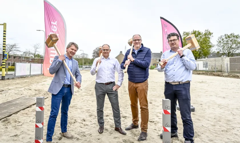 Vier mensen van betrokken partijen met hamers voor eerste paal JS Bachstraat