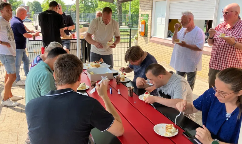 Mensen eten taart om samenwerking met SV Slikkerveer te vieren