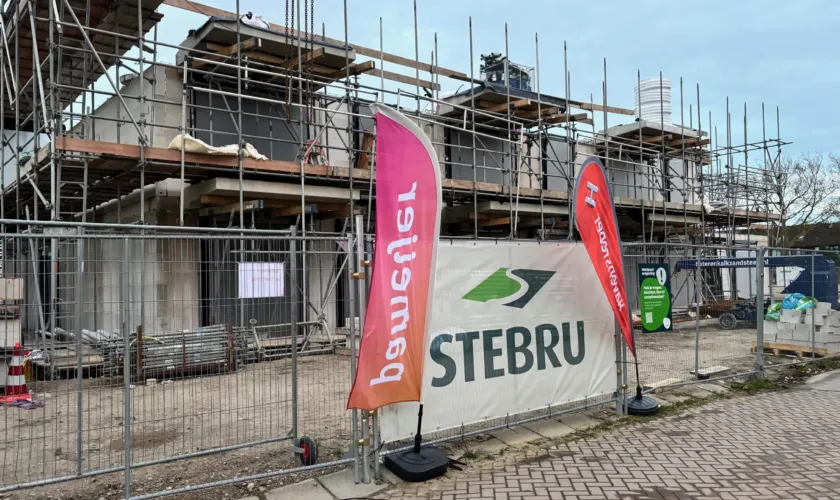 Een woongebouw in aanbouw, op de voorgrond vlaggen van Pameijer, Stebru en Havensteder.