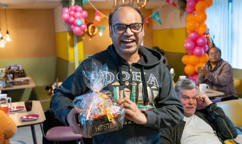 man houdt blij gewonnen feestpakket vast