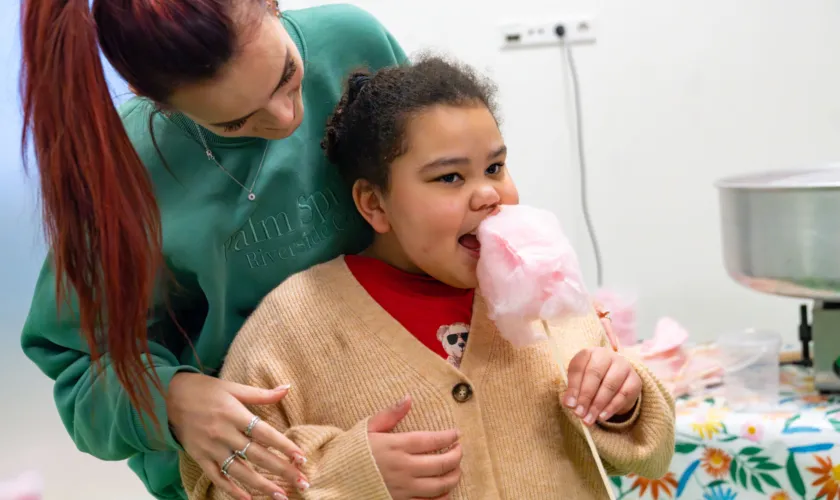 Vrouw staat achter kind dat suikerspin eet