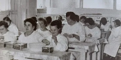 Oude foto van cliënten die gezamenlijk aan tafel zitten bij een werkproject