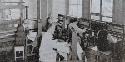 Oude foto van cliënten die werken met weefgetouwen