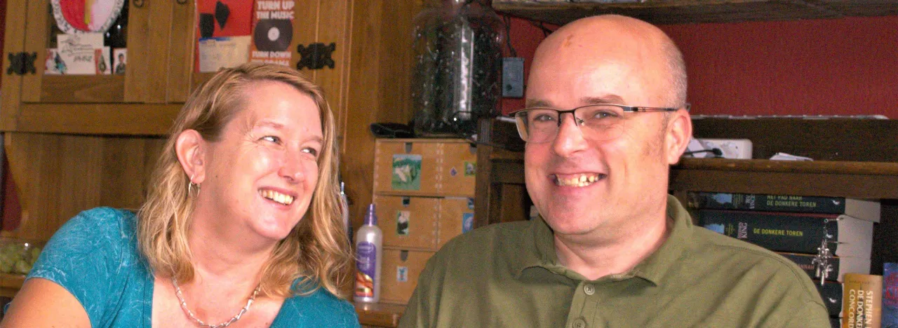 Man en vrouw zitten naast elkaar aan tafel met een kopje koffie