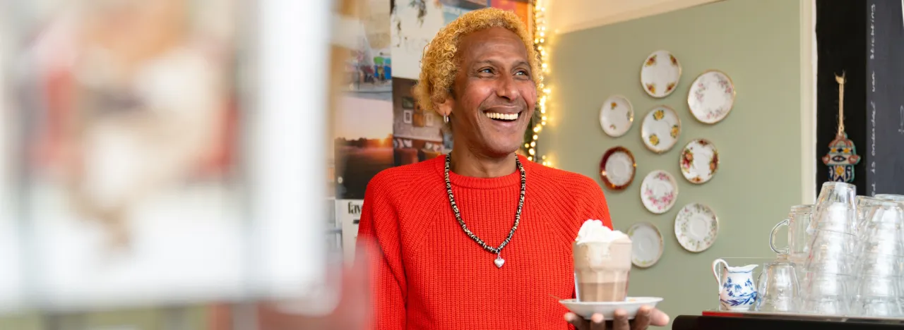 Medewerker horecaplek heeft een kopje koffie in zijn hand