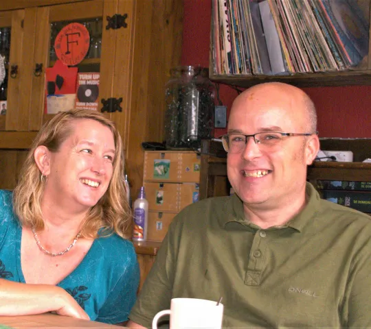 Man en vrouw zitten naast elkaar aan tafel met een kopje koffie