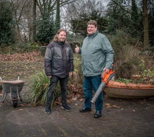 Twee mannen poseren in tuin met tuingereedschap om zich heen