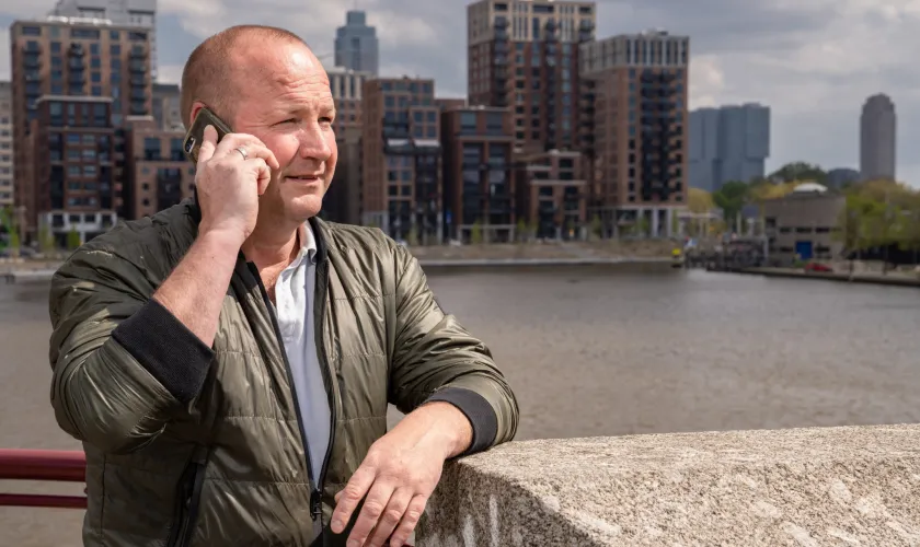 Man is aan de telefoon en op de achtergrond is de stad zichtbaar