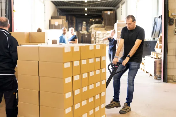 Een man verplaatst een grote stapel dozen met een elektrisch hulpmiddel