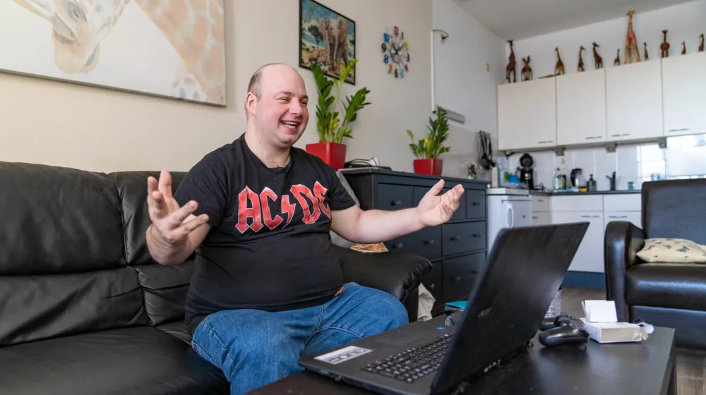 Man zit op de bank achter laptop