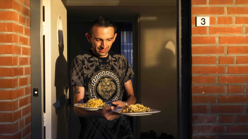 Een man loopt met twee borden pasta naar buiten