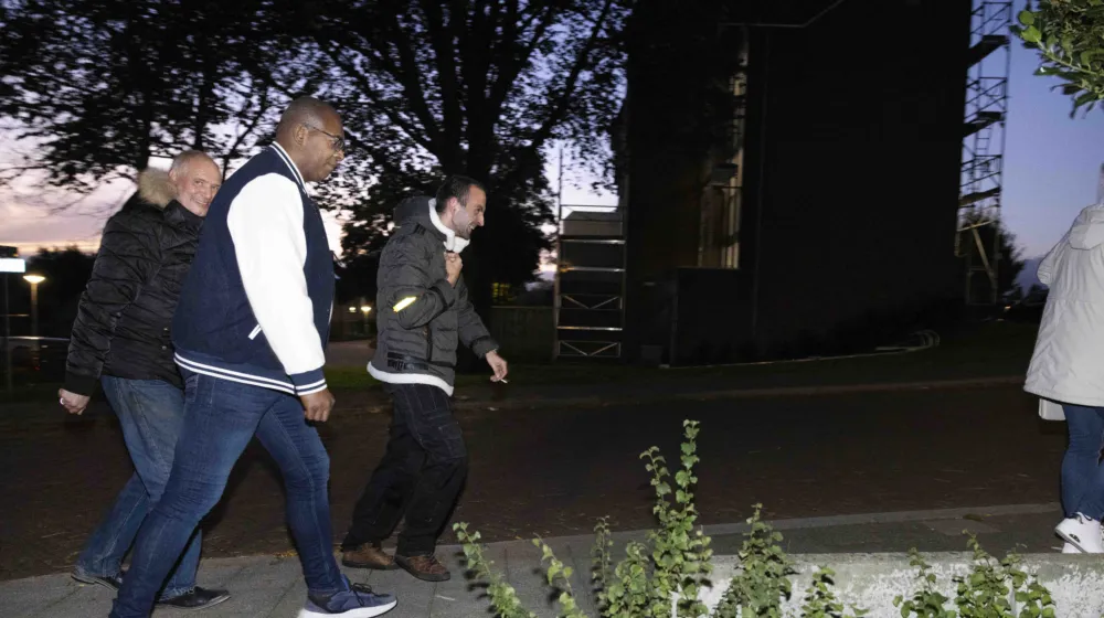 Drie mannen wandelen, het wordt al een beetje donker. Éen man kijkt in de camera en lacht