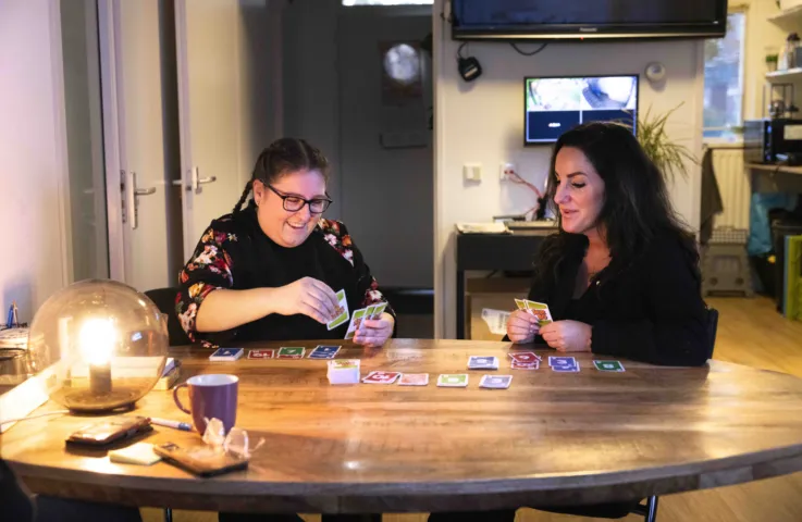 Twee vrouwen zitten aan tafel en spelen een potje Skipbo