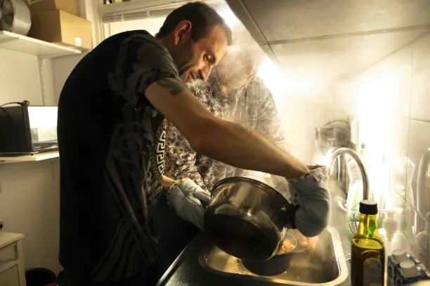 Twee mannen staan in de keuken en gieten het kookwater van de pan pasta af