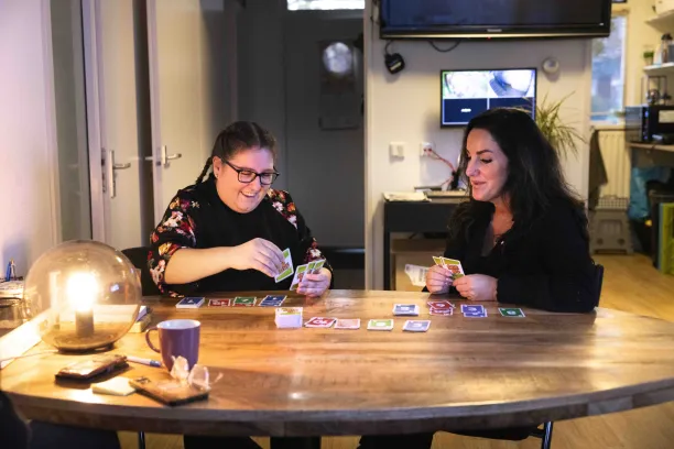 Twee vrouwen zitten aan tafel en spelen een potje Skipbo