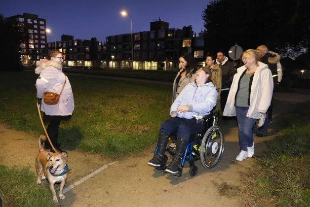 Een groep mensen wandelt met elkaar, éen vrouw zit in een rolstoel en er is ook een hondje bij